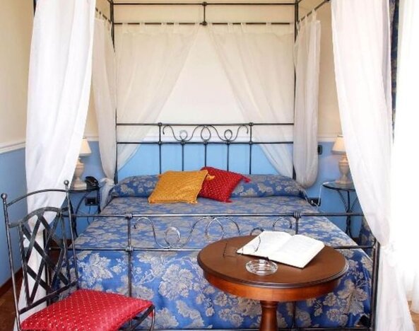 Romantic guest room with a wrought-iron canopy bed, hardwood flooring, and timeless décor.