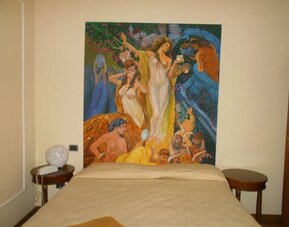 Comfortable guest room featuring a double bed, classic furnishings, and a striking decorative artwork.