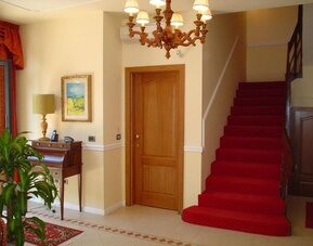 Elegant hotel lobby featuring classic furnishings, a grand staircase, chandelier lighting, and a welcoming atmosphere.