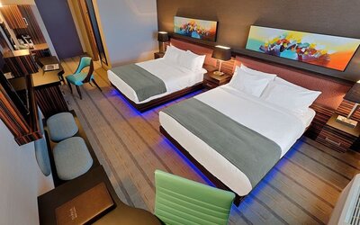 Guest room with two queen beds, workspace, seating area, and contemporary artwork above each headboard. Hotel Clique Calgary Airport.