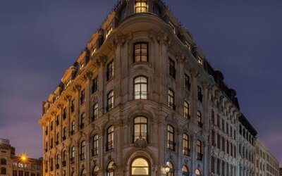 Historic stone hotel exterior illuminated at night on a corner street with arched entrance and tall windows. Hotel Gault.