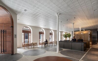 Spacious hotel lobby with reception desk, arched windows, dining tables, and contemporary seating areas. Hotel Gault.