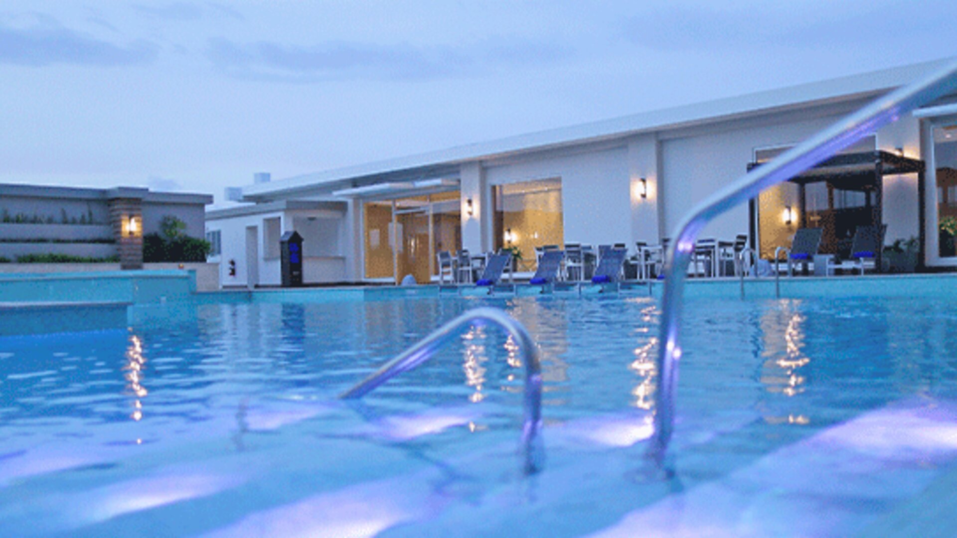 Outdoor swimming pool area at Crowne Plaza Panama Airport with spacious lounging areas and evening lighting, offering a relaxing environment for guests.