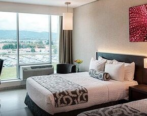 Modern guest room at Crowne Plaza Panama Airport featuring two comfortable beds, a workspace, large windows with city views, and contemporary décor designed for both business and leisure travelers.