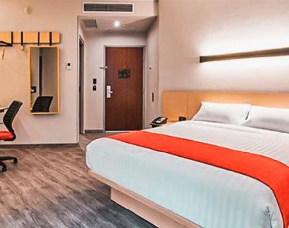Spacious guest room with a king-size bed, workspace, and modern amenities designed for both business and leisure stays.