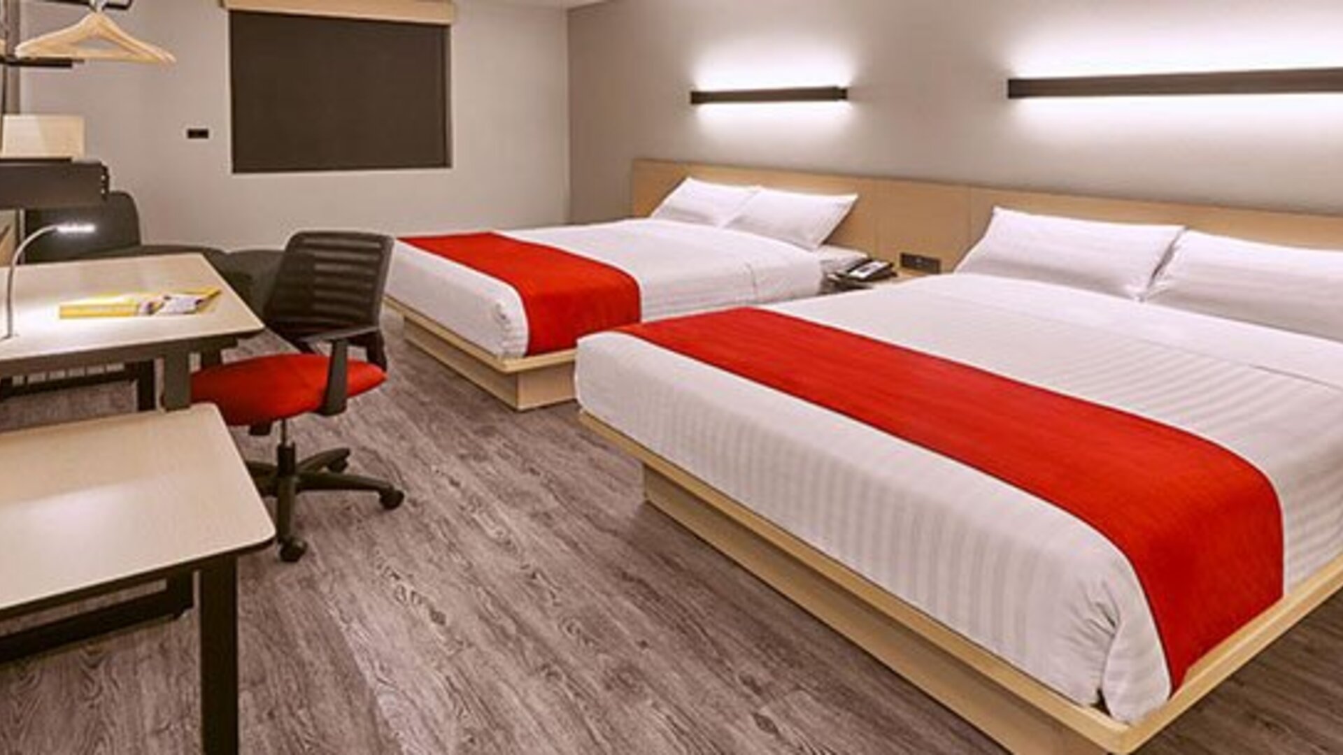 Modern guest room featuring two beds, dedicated workstations, contemporary furnishings, and comfortable accommodations for families or groups.