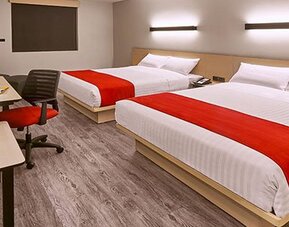 Modern guest room featuring two beds, dedicated workstations, contemporary furnishings, and comfortable accommodations for families or groups.