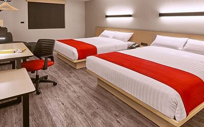 Modern guest room featuring two beds, dedicated workstations, contemporary furnishings, and comfortable accommodations for families or groups.