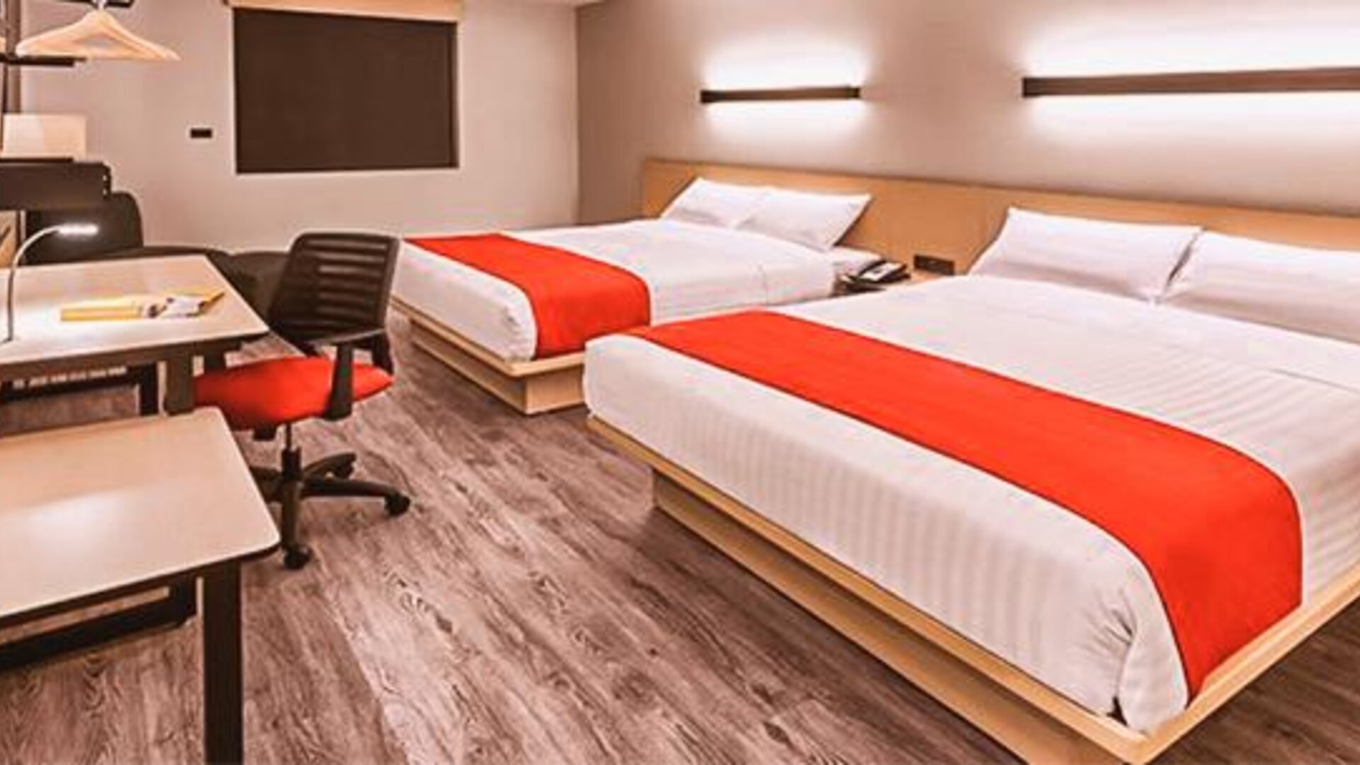 Modern guest room featuring two beds, dedicated workstations, contemporary furnishings, and comfortable accommodations for families or groups.