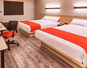 Modern guest room featuring two beds, dedicated workstations, contemporary furnishings, and comfortable accommodations for families or groups.