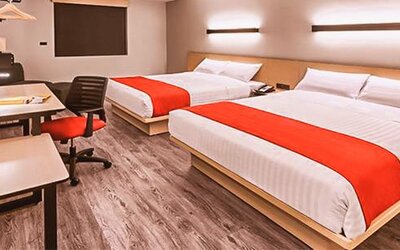 Modern guest room featuring two beds, dedicated workstations, contemporary furnishings, and comfortable accommodations for families or groups.