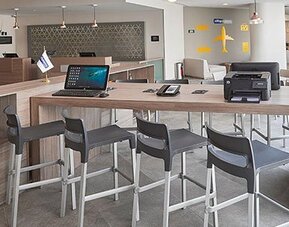 Business workspace with shared high-top tables, computer access, and convenient facilities for business travelers.