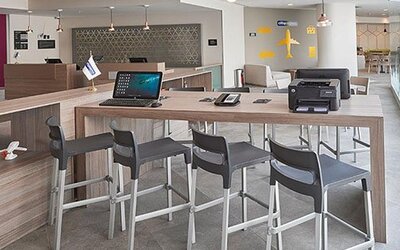 Business workspace with shared high-top tables, computer access, and convenient facilities for business travelers.