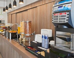 Complimentary breakfast station featuring hot beverages, juices, cereals, and a selection of morning dining options.