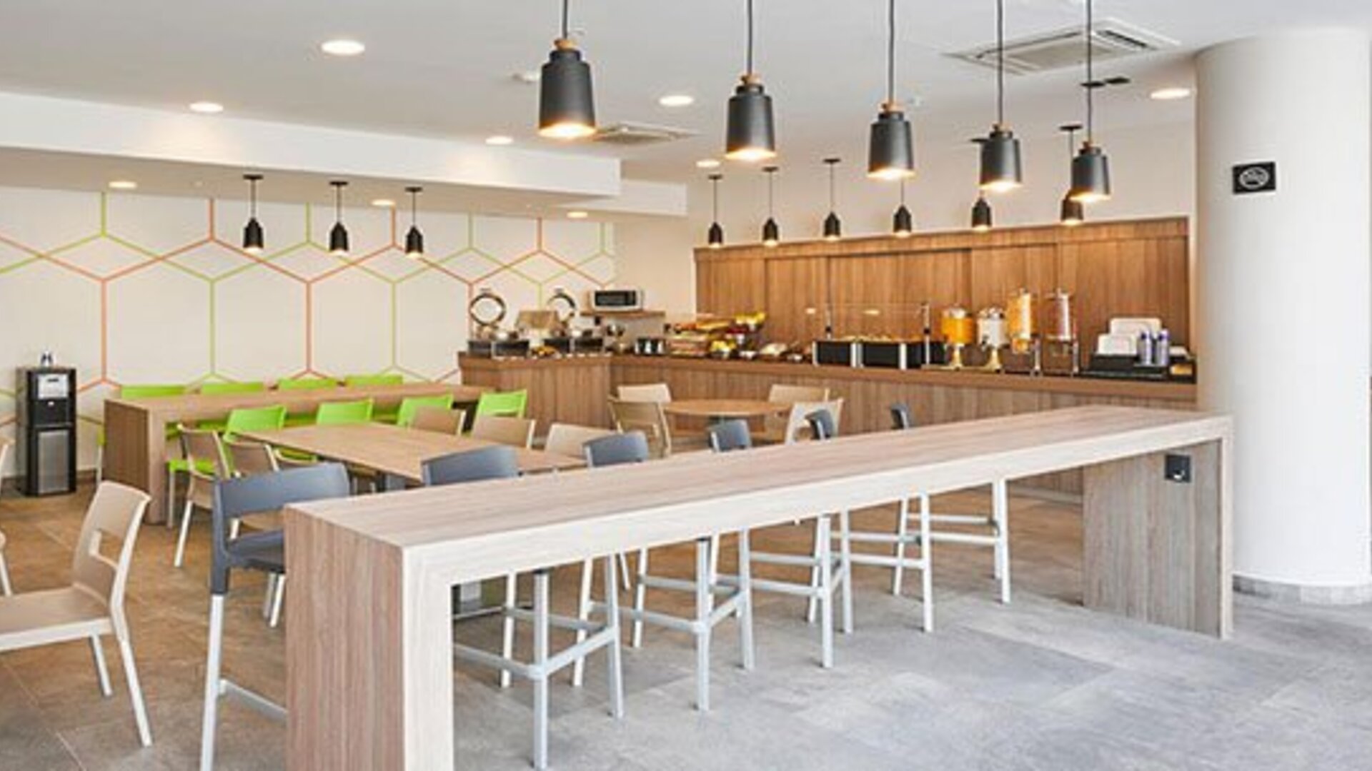 Contemporary breakfast and dining area with communal tables, buffet service, and ample seating for guests.