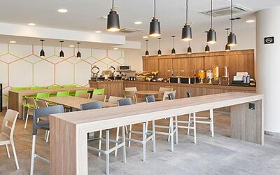 Contemporary breakfast and dining area with communal tables, buffet service, and ample seating for guests.