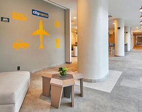 Hallway seating area near reception featuring modern décor and travel-themed accents within City Express by Marriott Aeropuerto Ciudad de México.