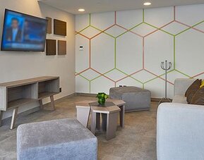 Comfortable lounge area with modern furnishings, television, and casual seating available for guests at City Express by Marriott Aeropuerto Ciudad de México.