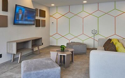 Comfortable lounge area with modern furnishings, television, and casual seating available for guests at City Express by Marriott Aeropuerto Ciudad de México.
