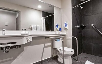 Accessible guest bathroom at City Express by Marriott Aeropuerto Ciudad de México featuring roll-in shower access, support rails, and modern fixtures designed for comfort and convenience.