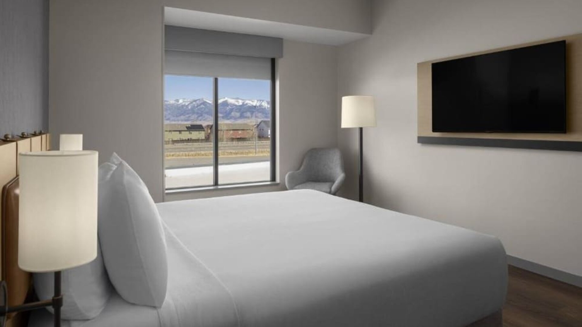 King guest room with mountain views, lounge chair, and wall-mounted television at Hyatt Place Bozeman Yellowstone Airport.