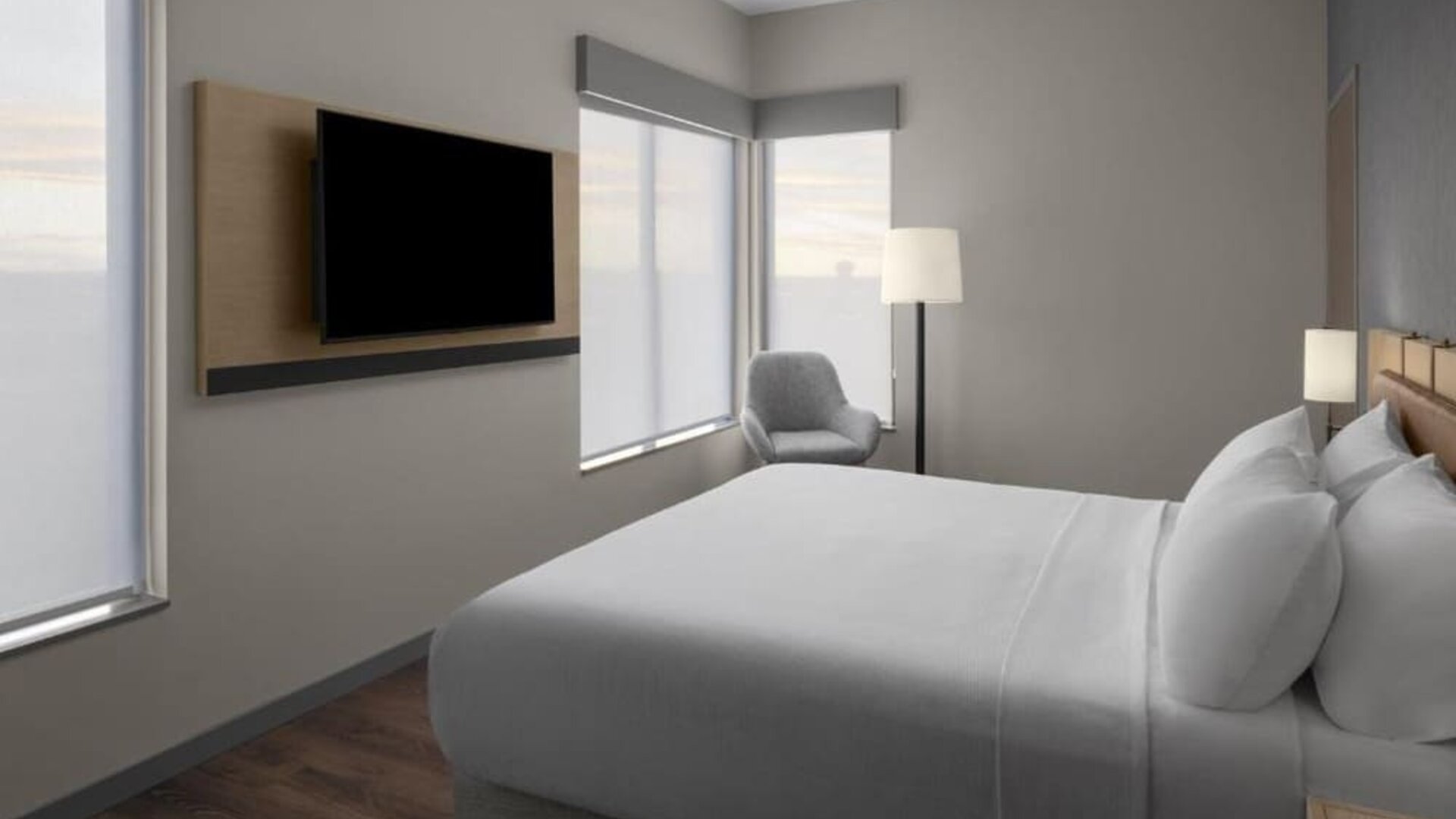 King guest room with large windows, wall-mounted television, lounge chair, and contemporary furnishings at Hyatt Place Bozeman Yellowstone Airport.