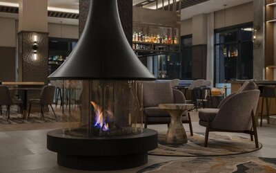Modern lobby lounge featuring a suspended fireplace, comfortable seating, and inviting social spaces at Hyatt Place Bozeman Yellowstone Airport.
