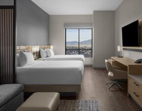 Guest room with two queen beds, work desk, sofa, and scenic mountain views at Hyatt Place Bozeman Yellowstone Airport.