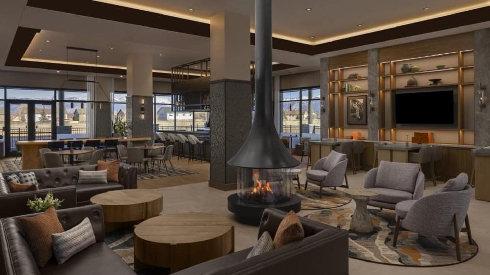 Spacious lobby with fireplace, lounge seating, bar area, and contemporary décor at Hyatt Place Bozeman Yellowstone Airport.