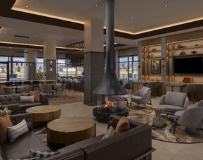 Spacious lobby with fireplace, lounge seating, bar area, and contemporary décor at Hyatt Place Bozeman Yellowstone Airport.