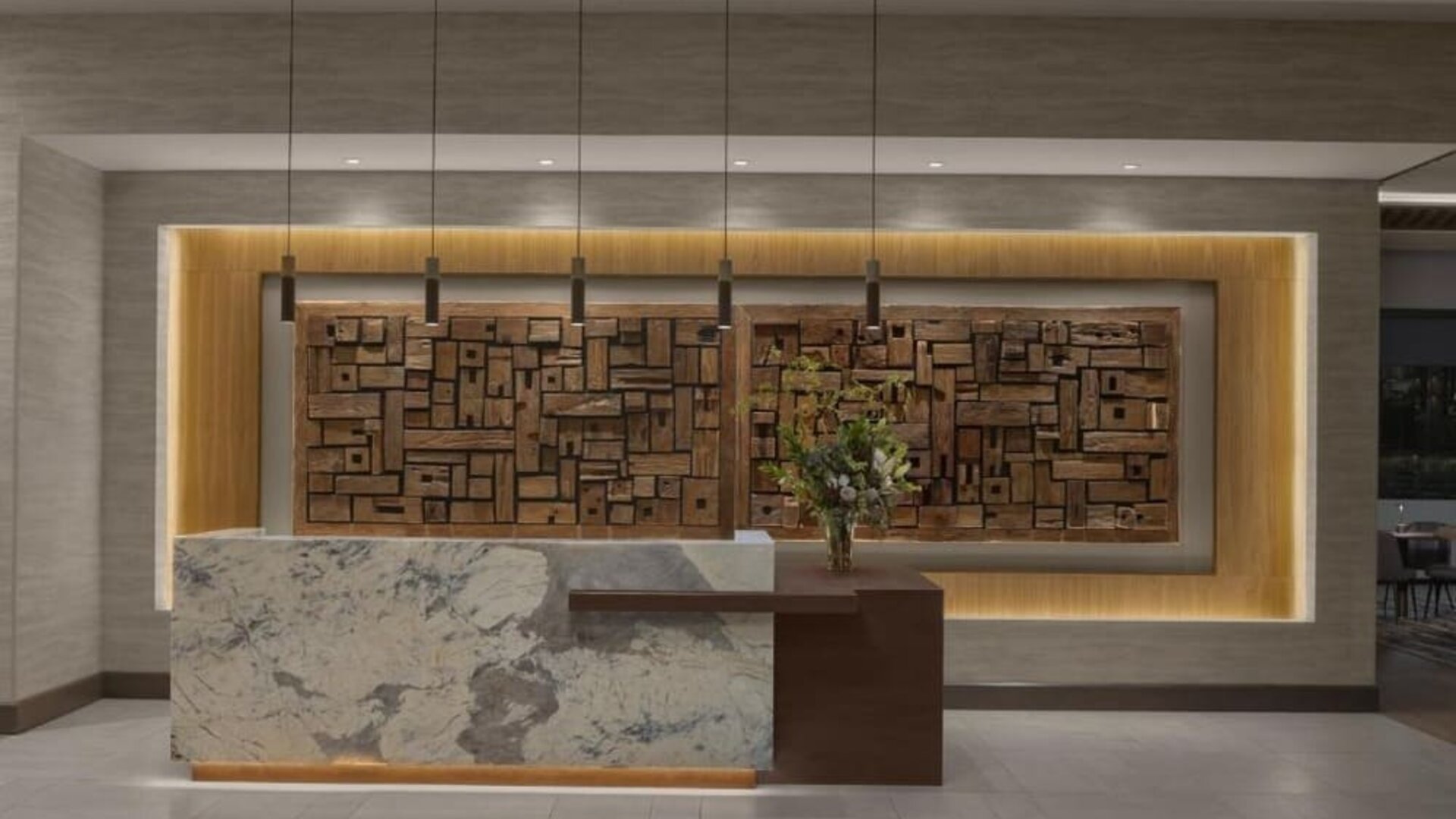 Reception desk with marble front, wood accent wall, and contemporary lighting at Hyatt Place Bozeman Yellowstone Airport.