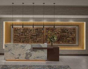 Reception desk with marble front, wood accent wall, and contemporary lighting at Hyatt Place Bozeman Yellowstone Airport.