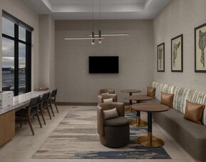 Business lounge with workstations, lounge seating, and wall-mounted television at Hyatt Place Bozeman Yellowstone Airport.