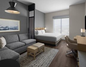 Spacious king guest room with sofa, work desk, and modern furnishings at Hyatt Place Bozeman Yellowstone Airport.