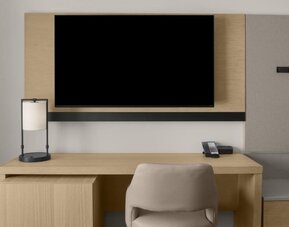 In-room workspace with desk, chair, telephone, and wall-mounted television at Hyatt Place Bozeman Yellowstone Airport.