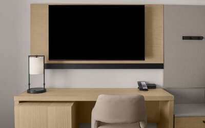 In-room workspace with desk, chair, telephone, and wall-mounted television at Hyatt Place Bozeman Yellowstone Airport.