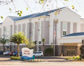 Hotel exterior with covered entrance, landscaped grounds, and guest parking at Hampton Inn & Suites Orlando at SeaWorld.