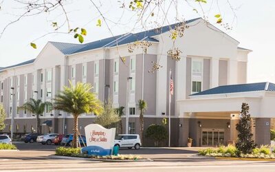 Hotel exterior with covered entrance, landscaped grounds, and guest parking at Hampton Inn & Suites Orlando at SeaWorld.