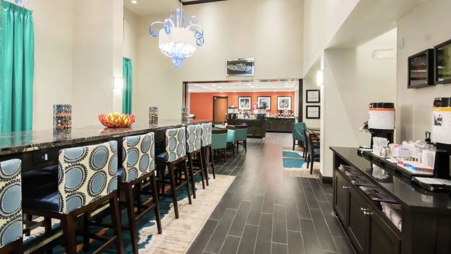 Hotel dining area with coffee station, communal seating, and breakfast service at Hampton Inn & Suites Orlando at SeaWorld.