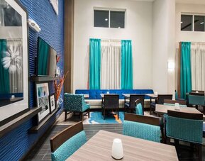 Lobby lounge with dining tables, seating area, and high ceilings at Hampton Inn & Suites Orlando at SeaWorld.