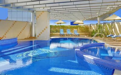 Covered outdoor pool with curved design, lounge chairs, shaded seating areas, and relaxing leisure space.