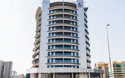 Contemporary high-rise hotel building with curved architectural design, glass windows, and city surroundings.