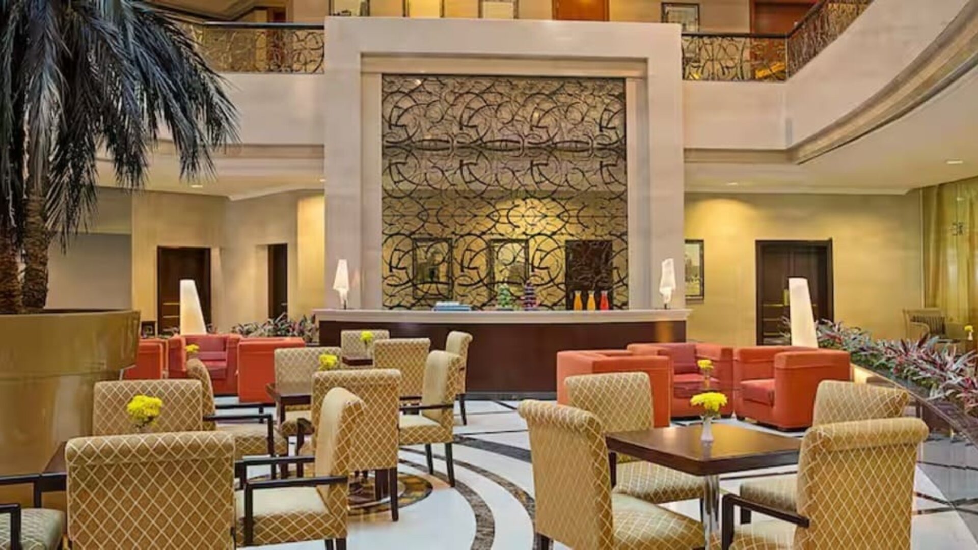 Elegant hotel lobby with comfortable seating, decorative wall feature, indoor palm accents, and welcoming atmosphere.