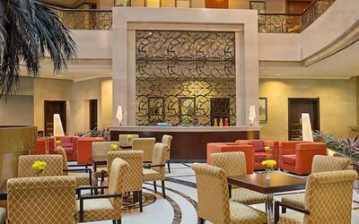 Elegant hotel lobby with comfortable seating, decorative wall feature, indoor palm accents, and welcoming atmosphere.