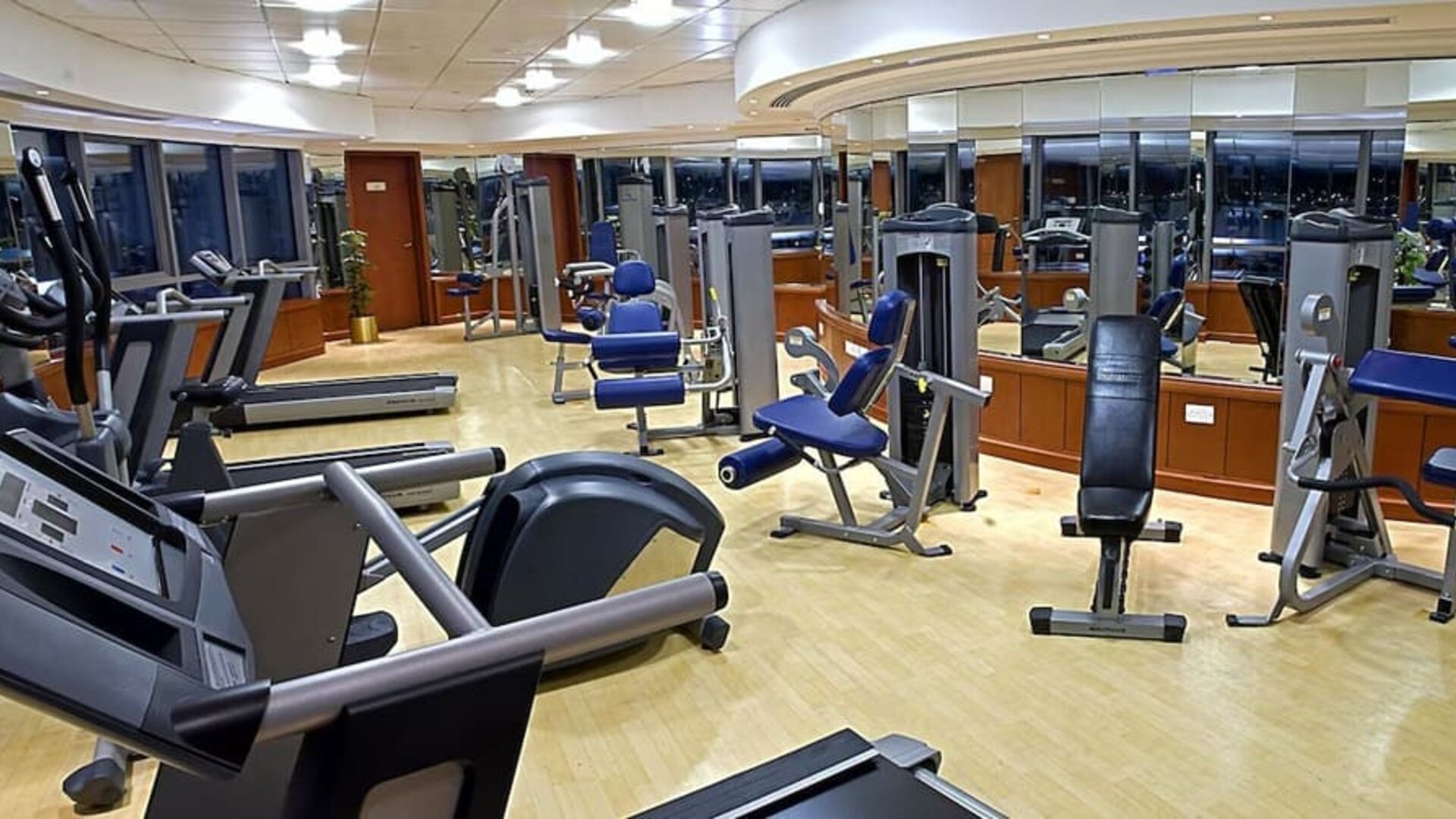 Modern fitness center with treadmills, cardio machines, weight equipment, mirrored walls, and spacious workout areas.