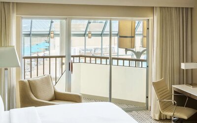 Spacious king room with plush bed, work desk, lounge chair, large window, and scenic outdoor view.