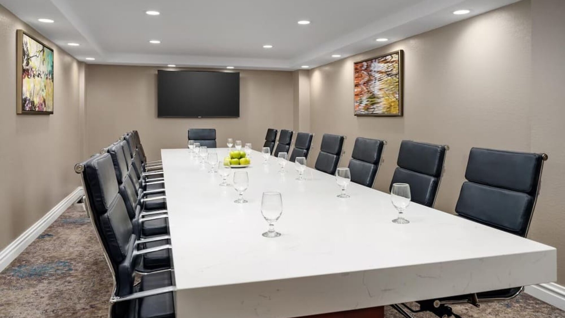 Private meeting room with long conference table, leather executive chairs, and wall-mounted display.