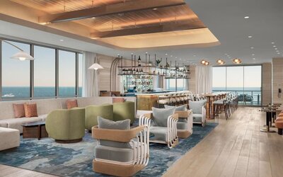 Spacious lounge and bar area with ocean views, plush seating, wood flooring, and contemporary coastal décor.