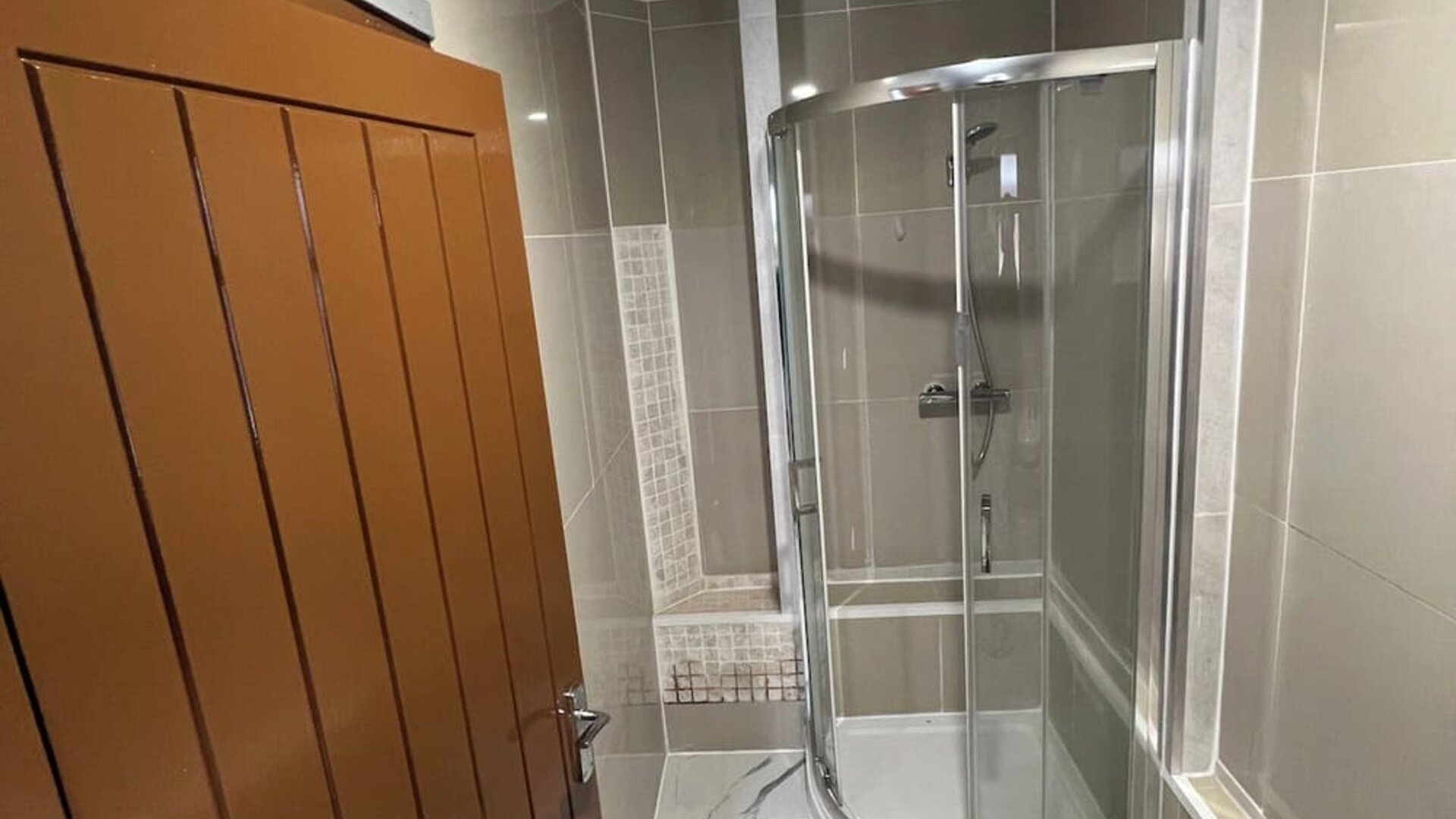 Modern bathroom with glass-enclosed shower, tiled walls, and contemporary finishes at Stay Inn Express.