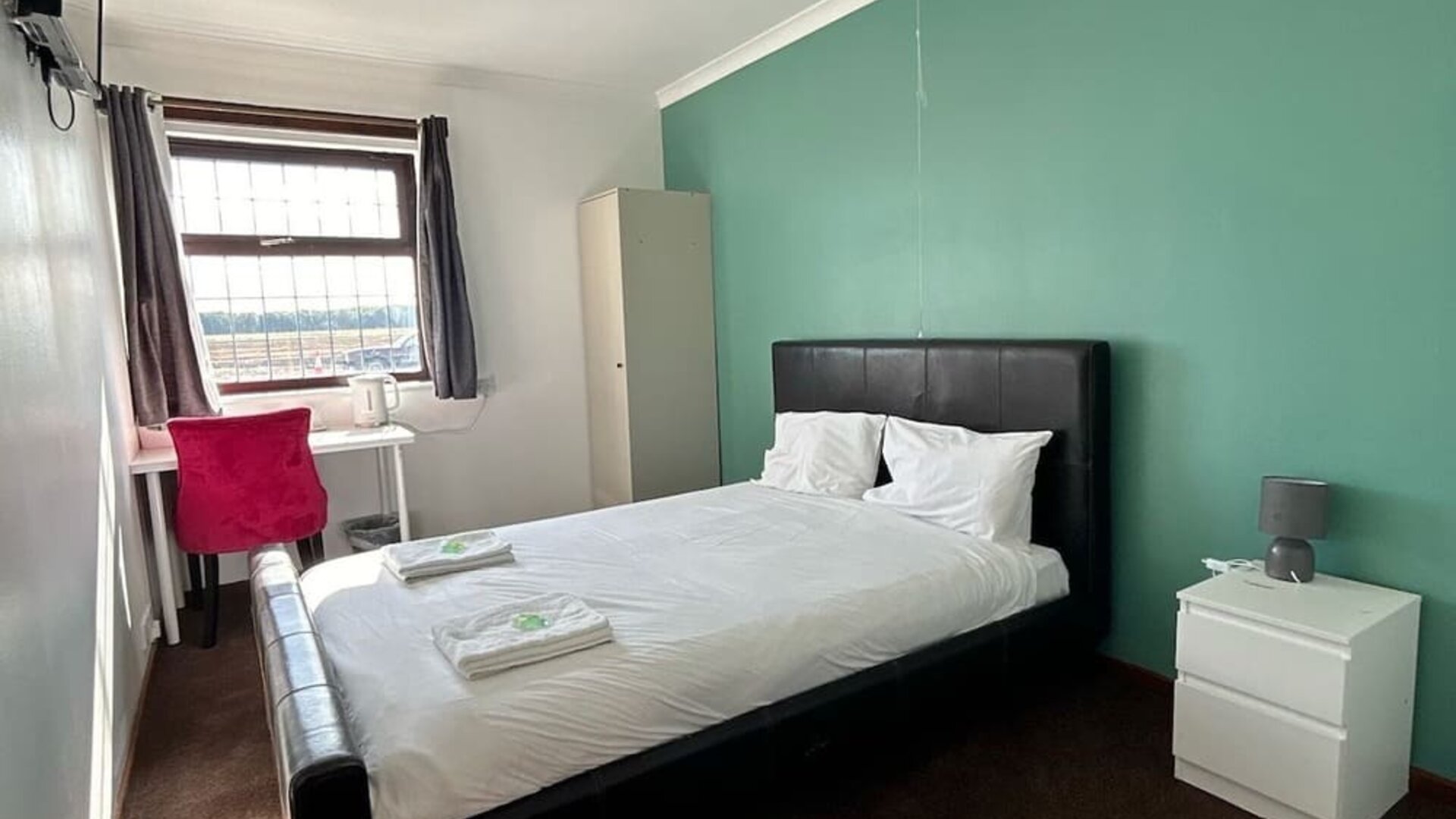 Bright guest room with double bed, work desk, wardrobe, and large window at Stay Inn Express.